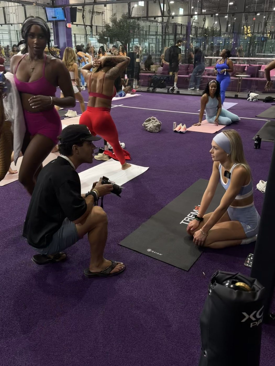 A photographer crouched shooting Madeline on a mat at a fitness event