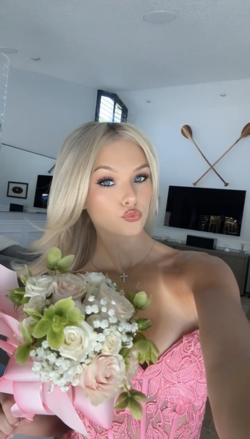 Selfie of Madeline in a pink dress holding roses